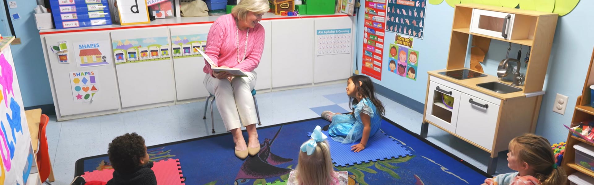 teacher reading book to preschool age children